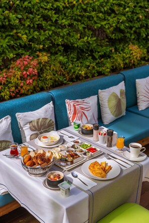 A breakfast table set outdoors with a variety of food items, a coffee cup, and a juice pitcher. - Ada Suites Nisantasi (Istanbul)