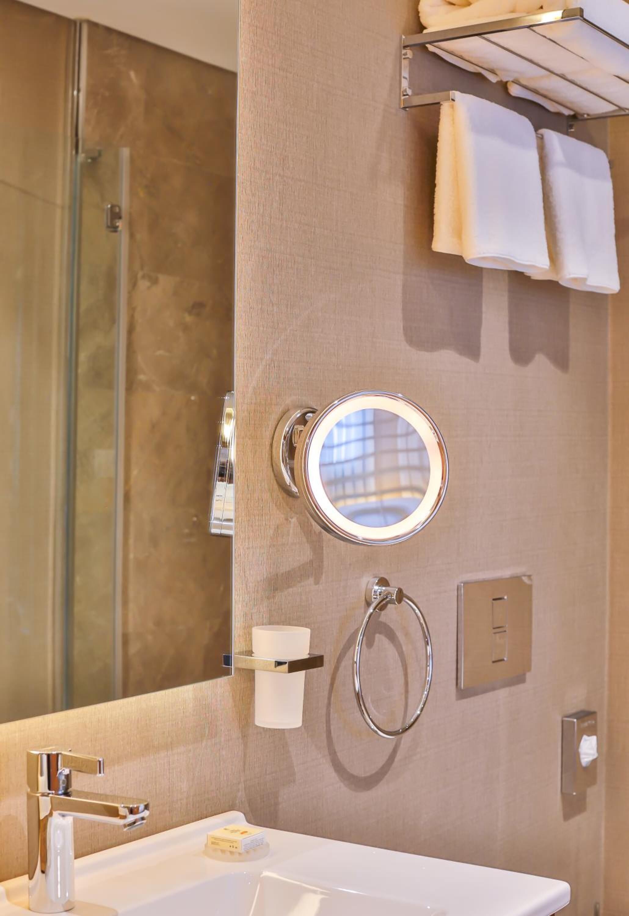 Une salle de bain avec une douche à parois de verre, un lavabo avec un miroir et un porte-serviettes avec des serviettes.