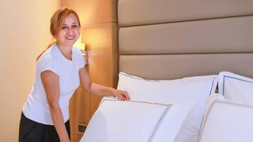 Una habitación de hotel con una cama grande, un cabecero de madera y una mesita de noche con una lámpara.