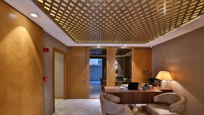 A hotel lobby with a wooden reception desk, two armchairs, a lamp, and a view into the dining area. - Ada Suites Nisantasi (Istanbul)