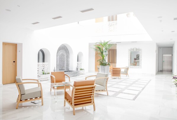 A spacious lobby with modern furniture, a central seating area, and a large window allowing natural light. - Soho Boutique Capuchinos & Spa (Córdoba)