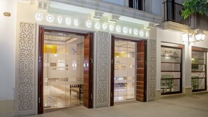 Het uiterlijk van Hotel Capuchinos, met sierlijke houten deuren en een goed verlichte ingang.
