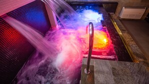 Een hottub met kleurrijk licht en een metalen reling.