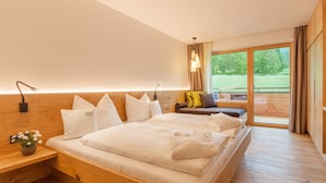 Un dormitorio moderno con una cama grande, una mesita de noche con un florero, un sofá y vistas al exterior.