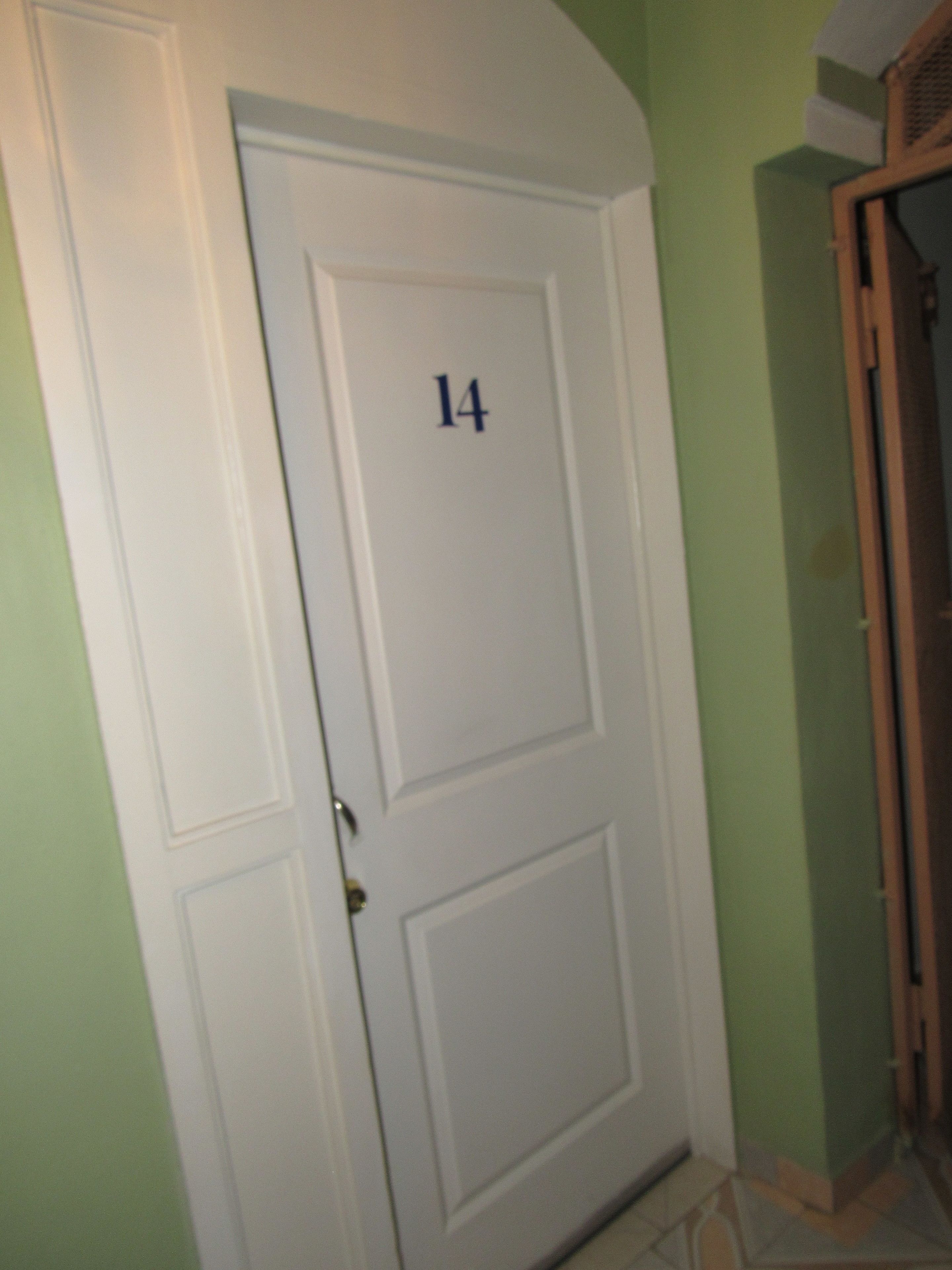 A white door with the number 14, a door handle, and a small window above it.