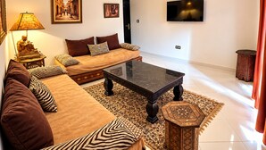 A living room with a sofa, a coffee table, a TV, and decorative items. - Hotel Tafoukt (Marrakech)