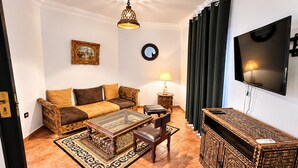 A living room with a sofa, coffee table, TV, and decorative items. - Hotel Tafoukt (Marrakech)