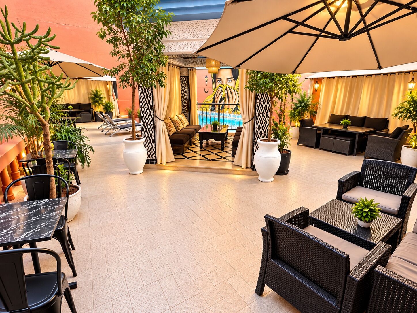 Een terras met tafels en stoelen, omringd door potplanten en een zwembad op de achtergrond.