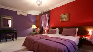 A bedroom with a large bed, a nightstand with a lamp, a dresser, and a mirror on the wall. - Hotel Tafoukt (Marrakech)