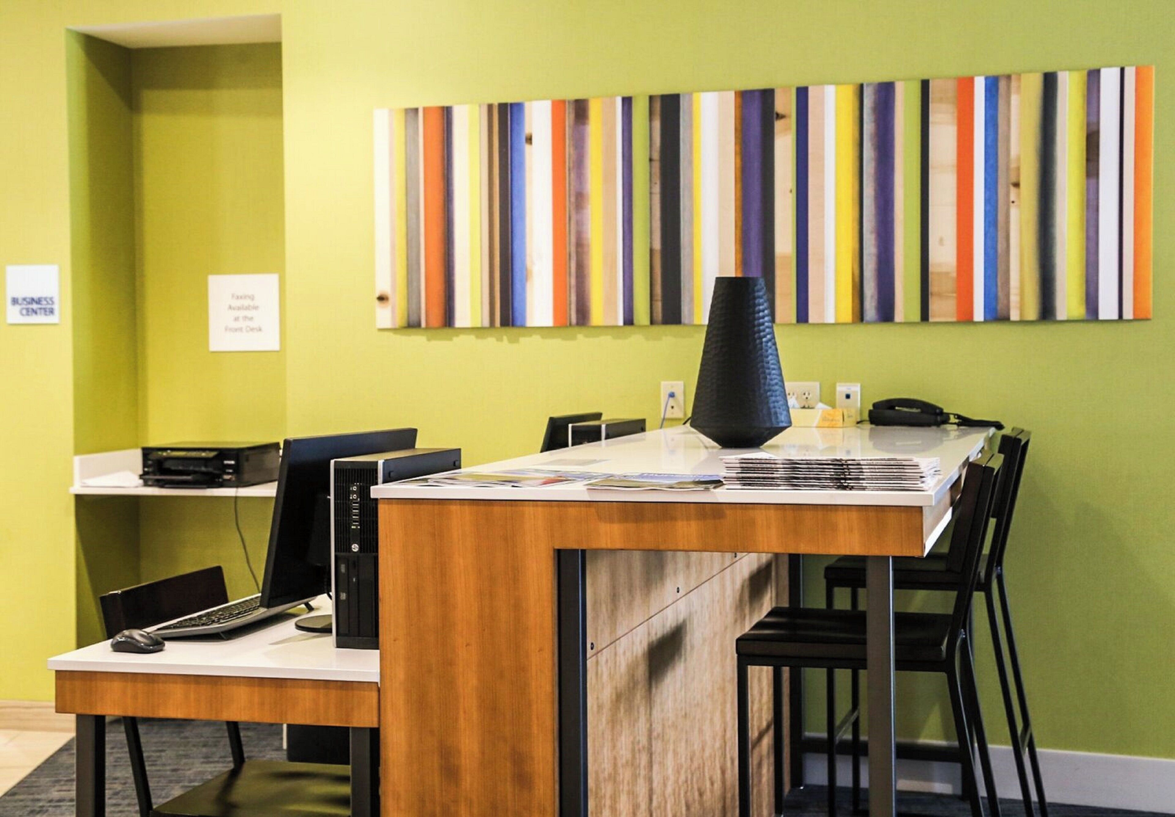 A reception desk with a computer, a phone, and a vase. There is a colorful striped wall art above the desk.