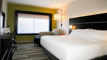 Quarto de hotel com uma cama grande, uma escrivaninha, uma cadeira e uma janela.