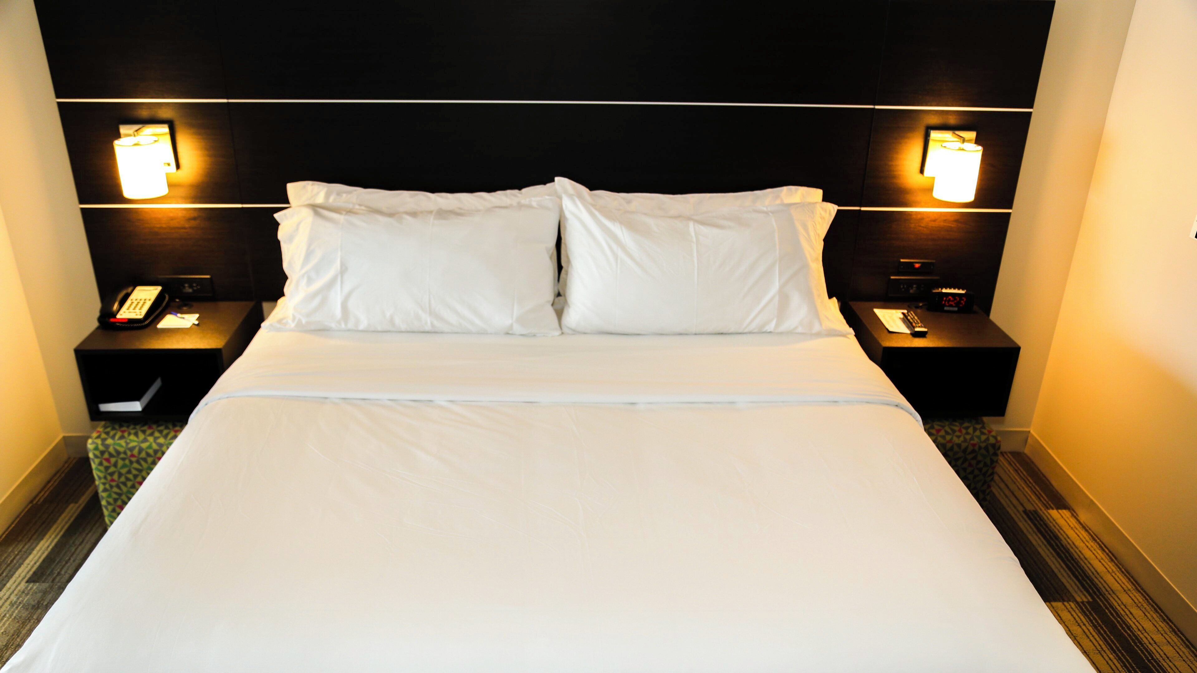 A hotel room with a large bed, two bedside tables, and two wall-mounted lamps.