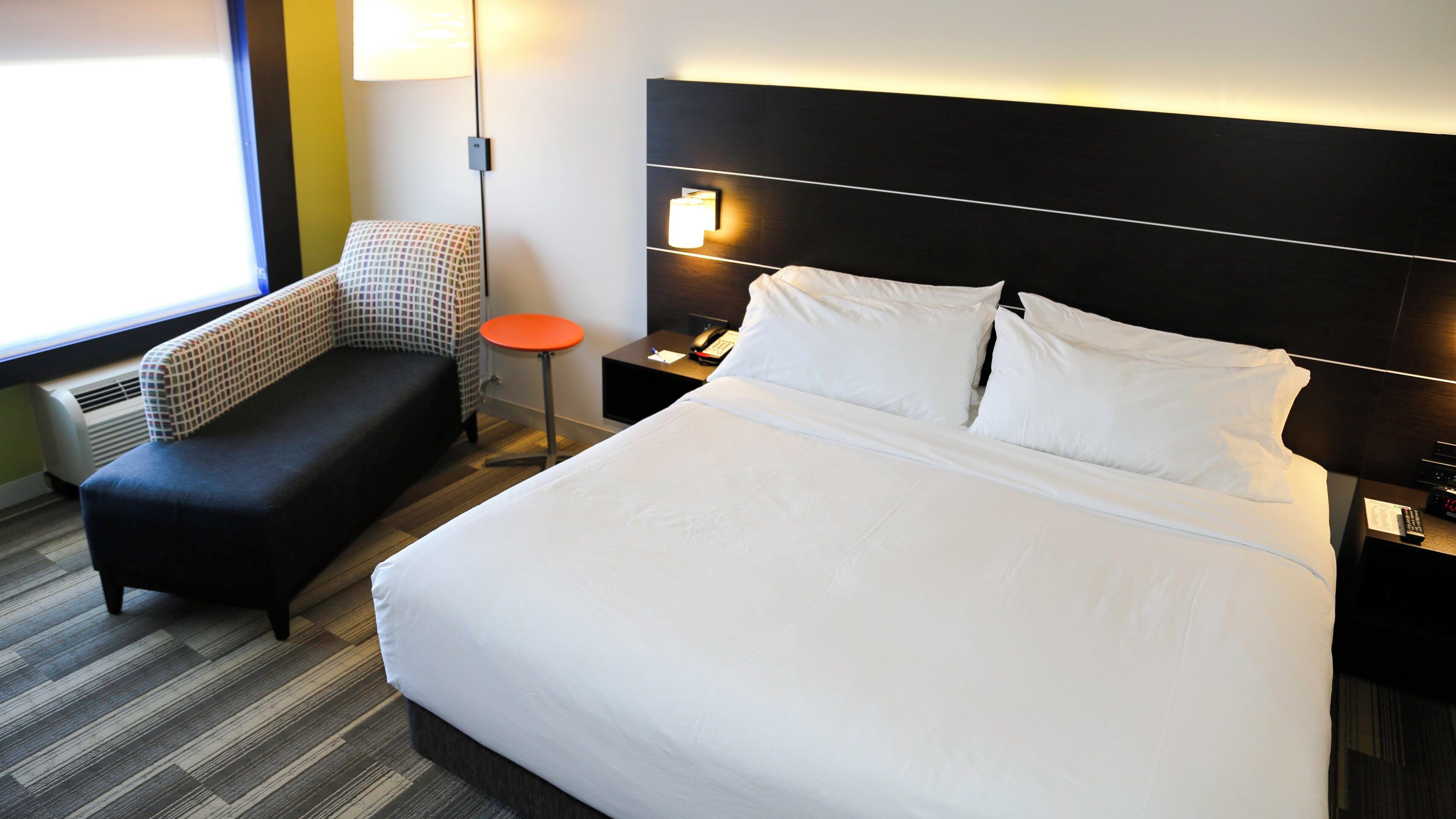 Ein Hotelzimmer mit einem großen Bett, einem kleinen Sofa, einem Nachttisch mit Telefon und einer Lampe.