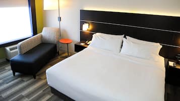 Ein Hotelzimmer mit einem großen Bett, einem kleinen Sofa, einem Nachttisch mit Telefon und einer Lampe.