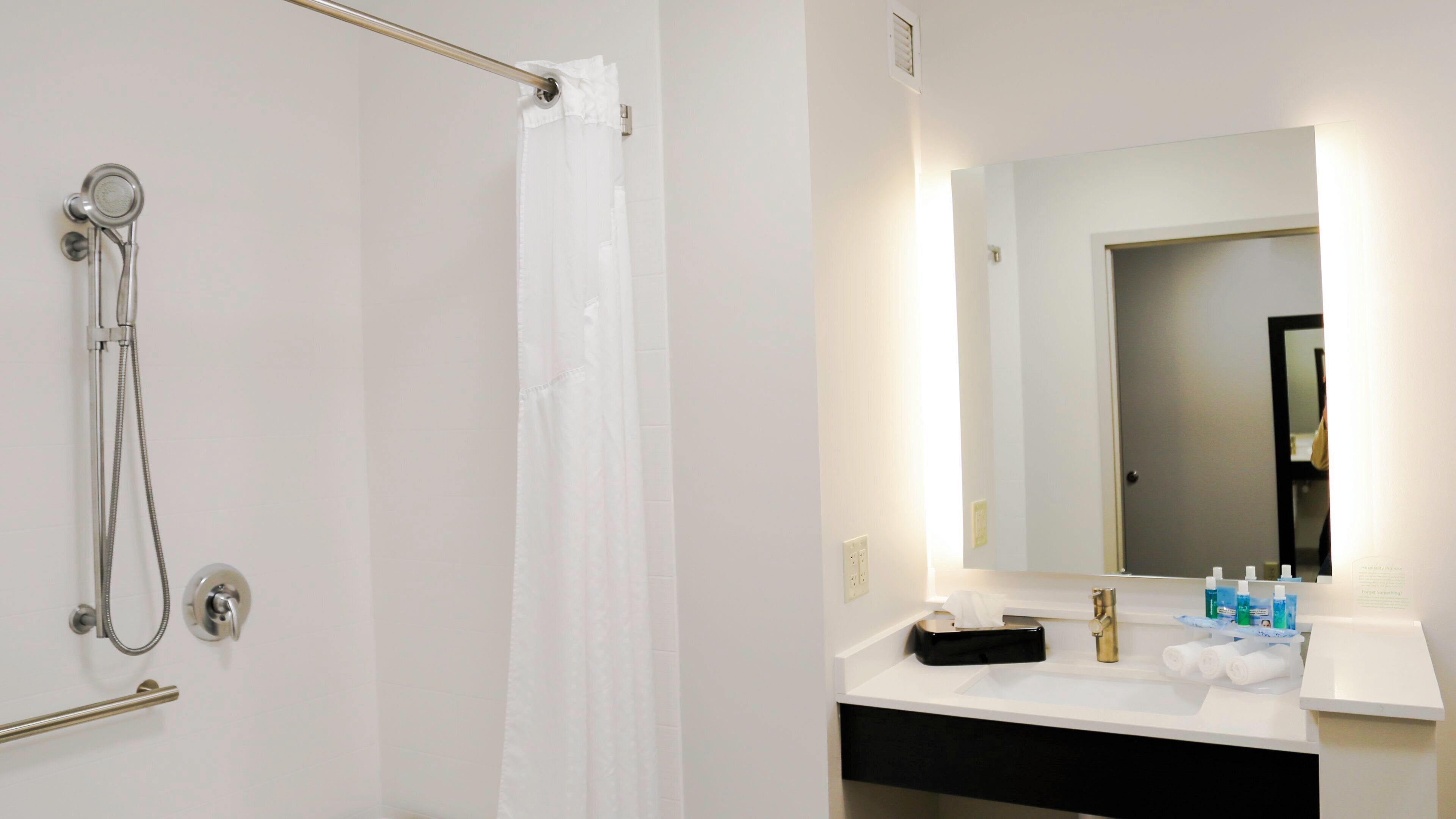 Ein Badezimmer mit Dusche, Waschbecken, Spiegel und Toilettenartikeln.