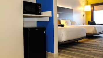 Quarto de hotel com cama, micro-ondas e geladeira.