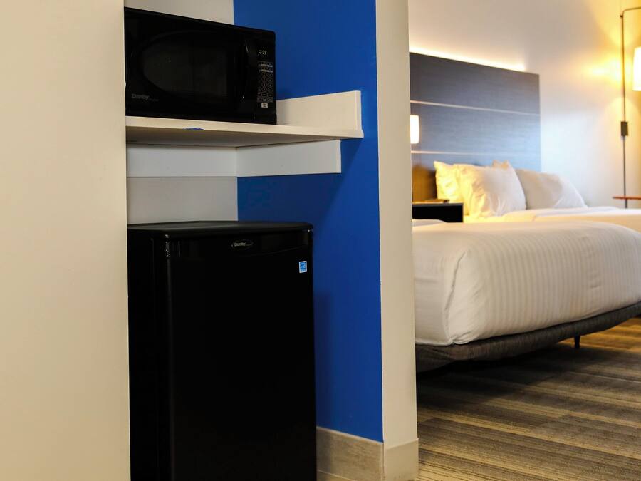 Quarto de hotel com cama, micro-ondas e geladeira.