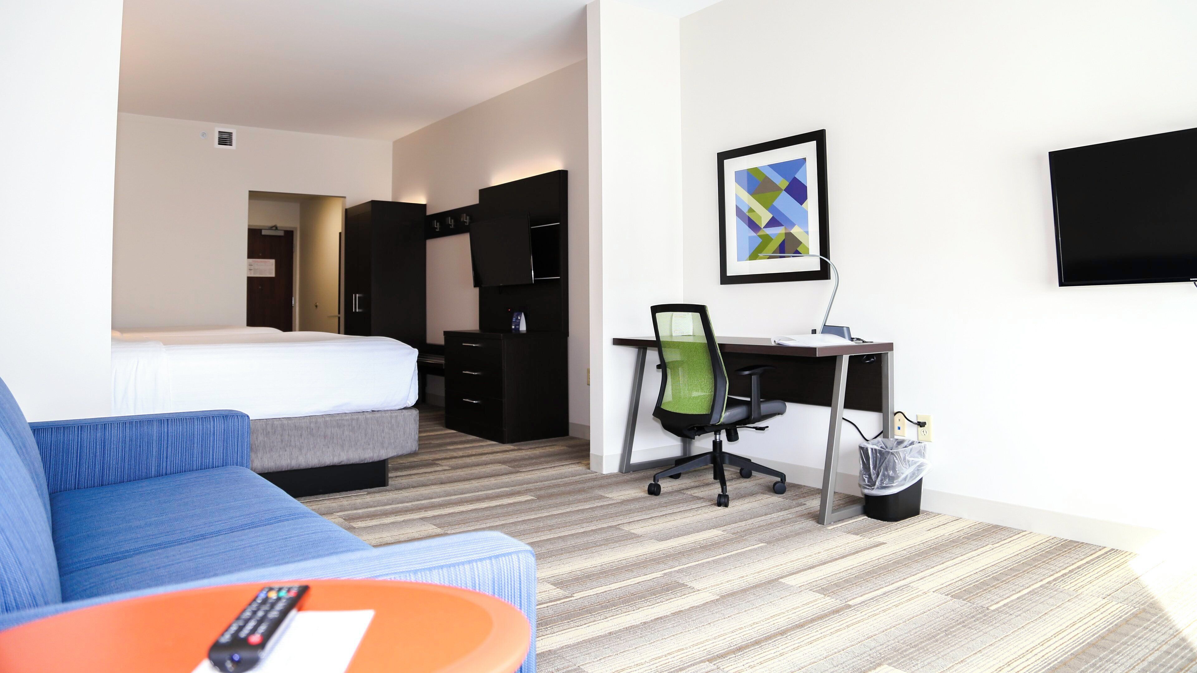 Una habitación de hotel con cama, escritorio con silla, televisor y sofá.