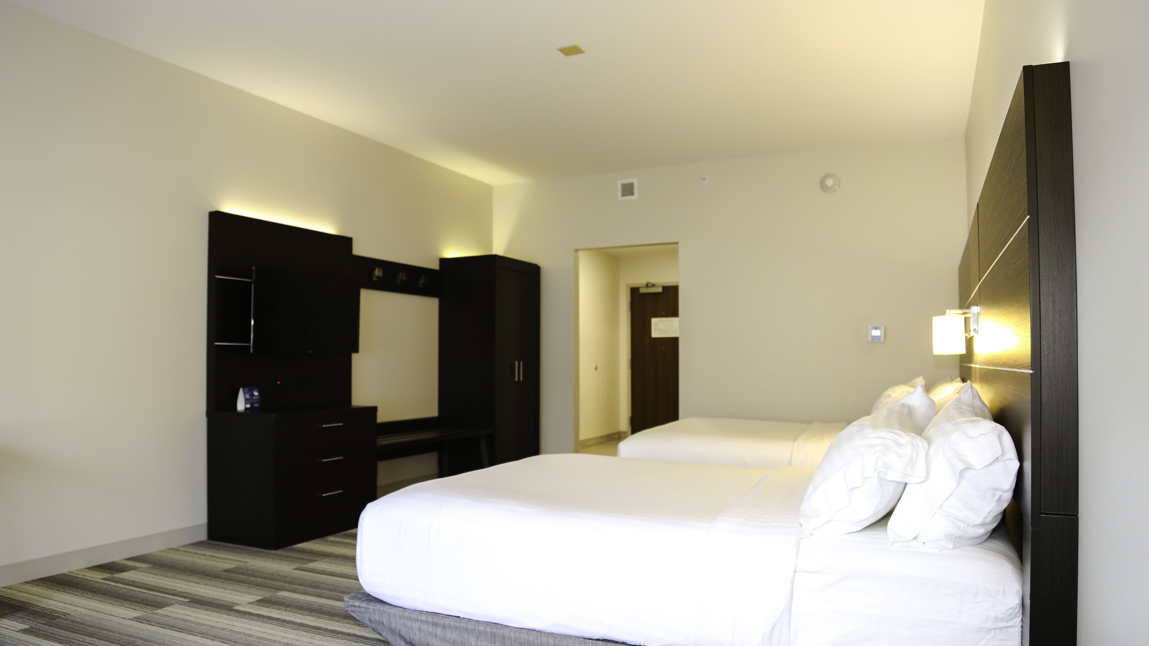 Una habitación de hotel con una cama grande, un armario, un escritorio y un espejo.
