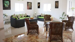 A spacious living area with a green sofa, wicker chairs, and artwork on the walls.