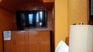A hotel room with a bed, a television on a wooden cabinet, a lamp, and a wall-mounted TV. - Hotel Real Azteca (Mexico City)