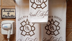 A bathroom with a towel rack holding two towels, a hairdryer, and a sign reading 'Secadora de Cabello'. - Hotel Real Azteca (Mexico City)