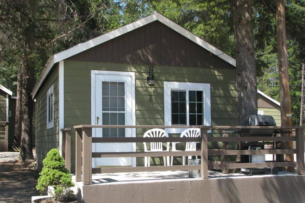 A small, single-story cabin with a porch and a small garden.