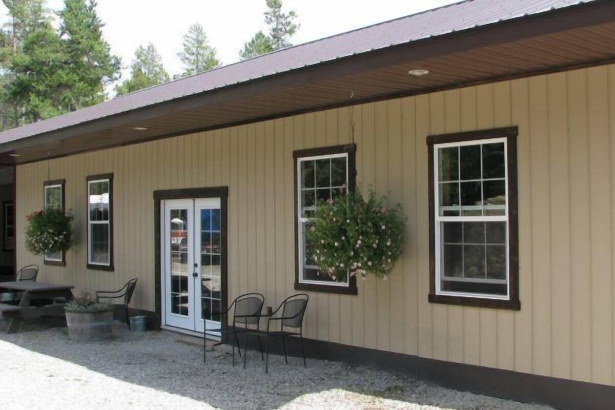 A building with a beige exterior, a covered patio area with outdoor seating, and potted plants.