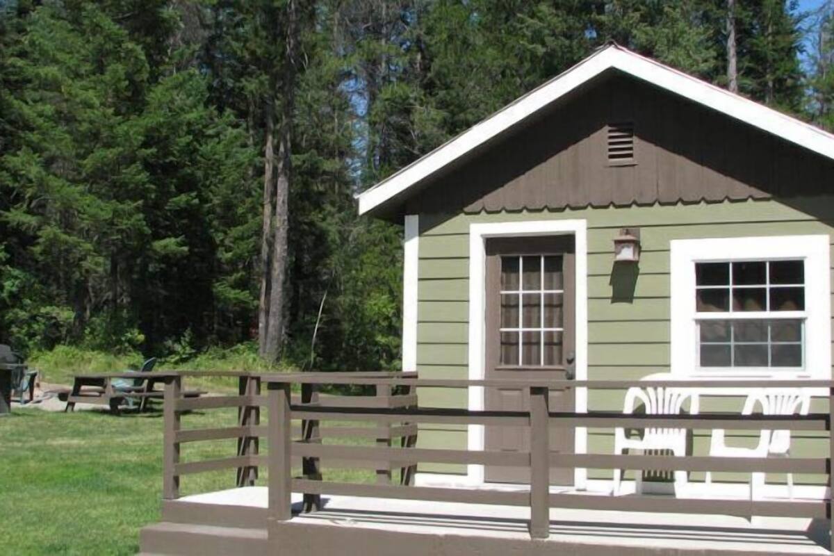 A small cabin with a wooden deck and a picnic table.