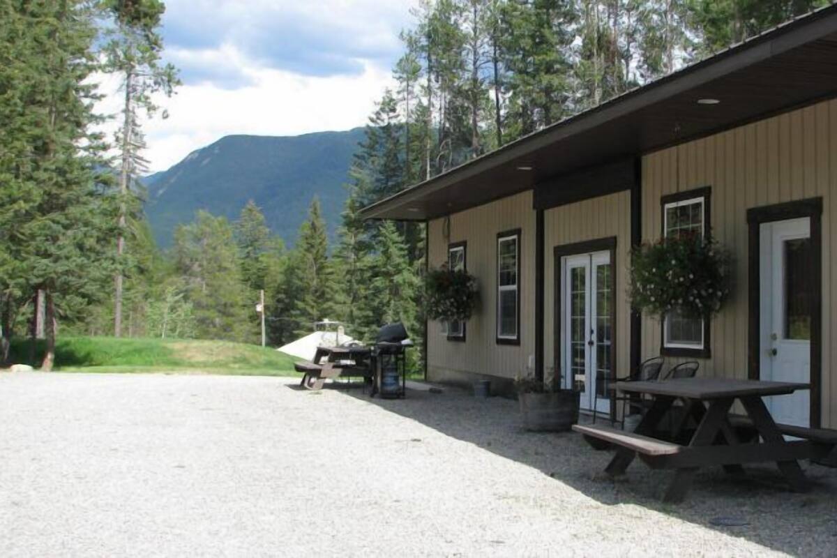 A building with a gravel driveway, a picnic table, and a mountain in the background.