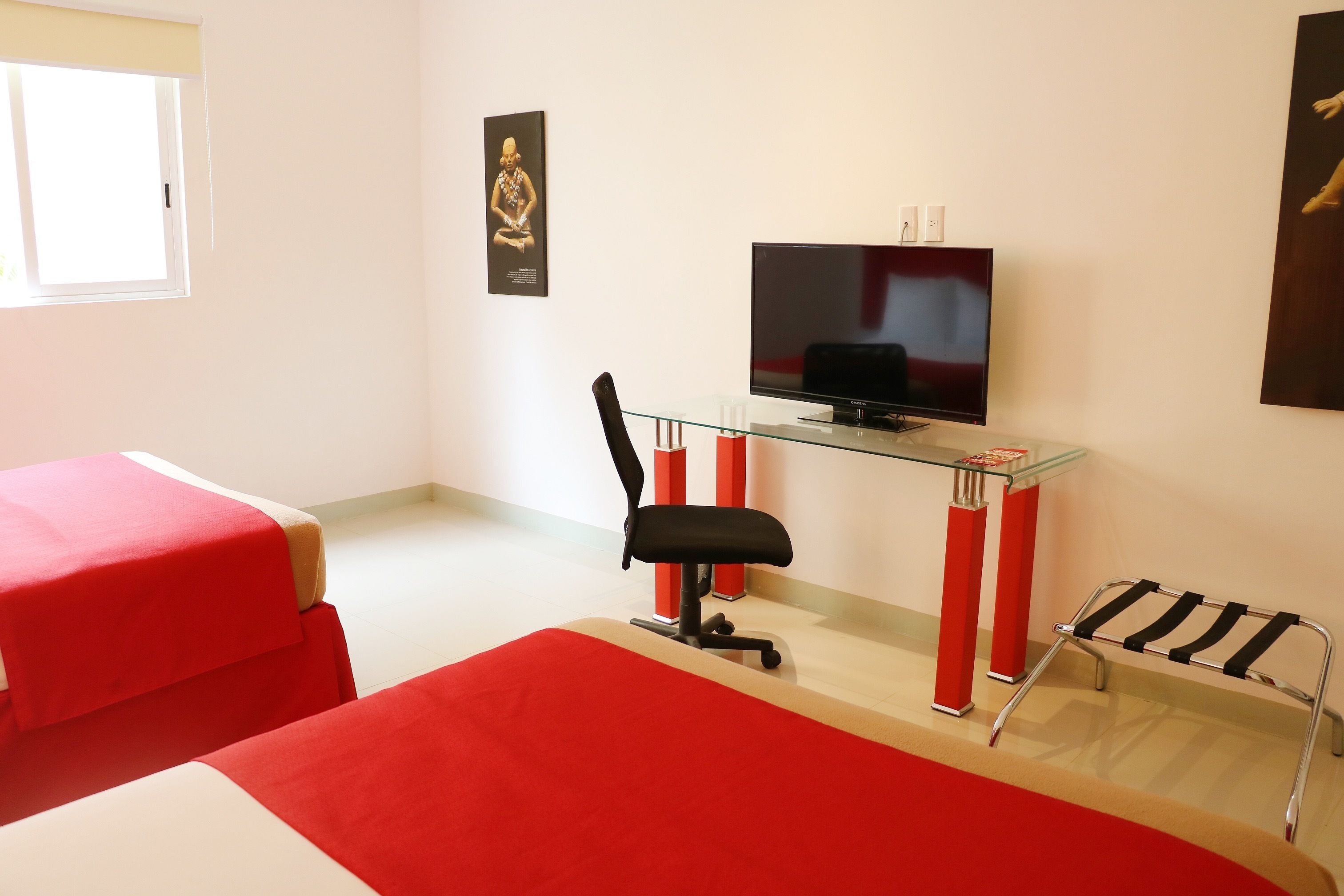 Une chambre avec un lit, un bureau avec un ordinateur, une chaise et un téléviseur.