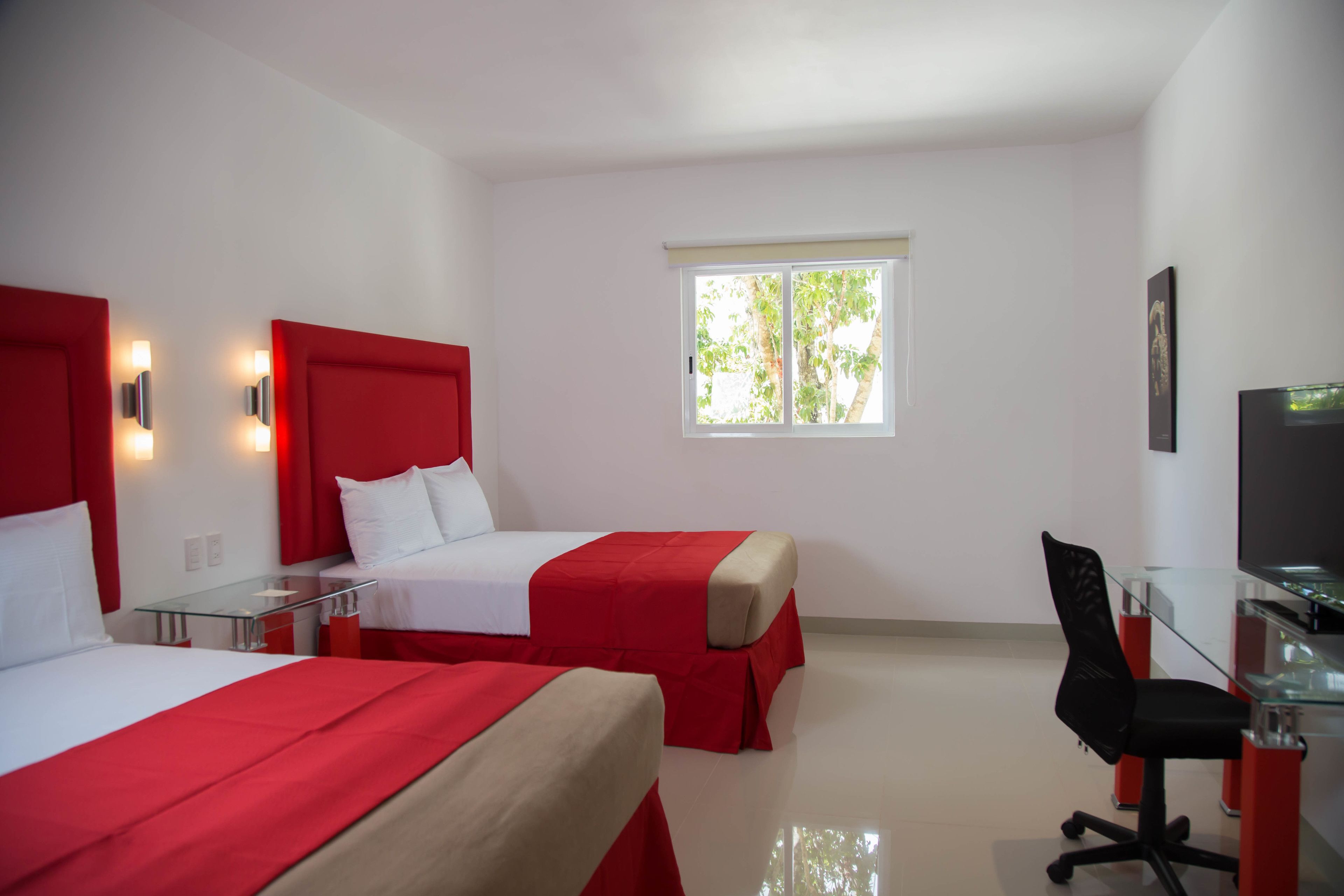 Una habitación de hotel con dos camas, un escritorio, una silla y un televisor.