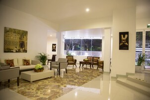 Un vestíbulo moderno con un sofá, sillones, una mesa de centro y un ventanal grande.