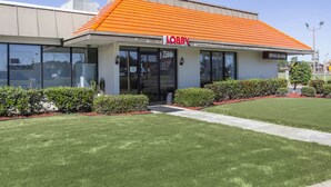 Um edifício com uma placa indicando “LOBBY” e uma placa com a mensagem “ABERTO 24 HRS”.