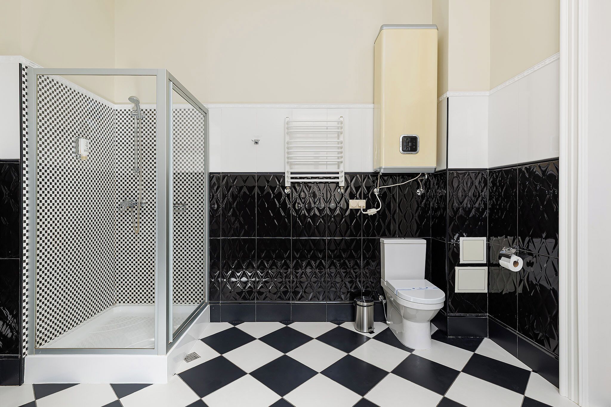 A bathroom with a checkered floor, a toilet, a shower, and a towel rack.