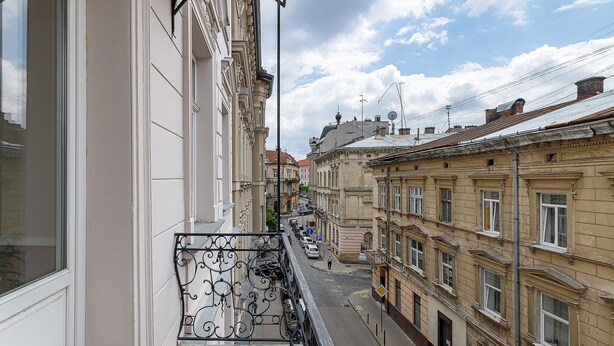 A narrow street with buildings on both sides, a pedestrian walkway, and a clear sky. - Modern Art Hotel - Maestro (Lviv)