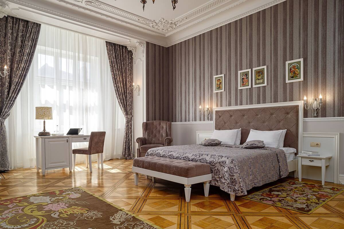 A bedroom with a large bed, a desk, and a chair.