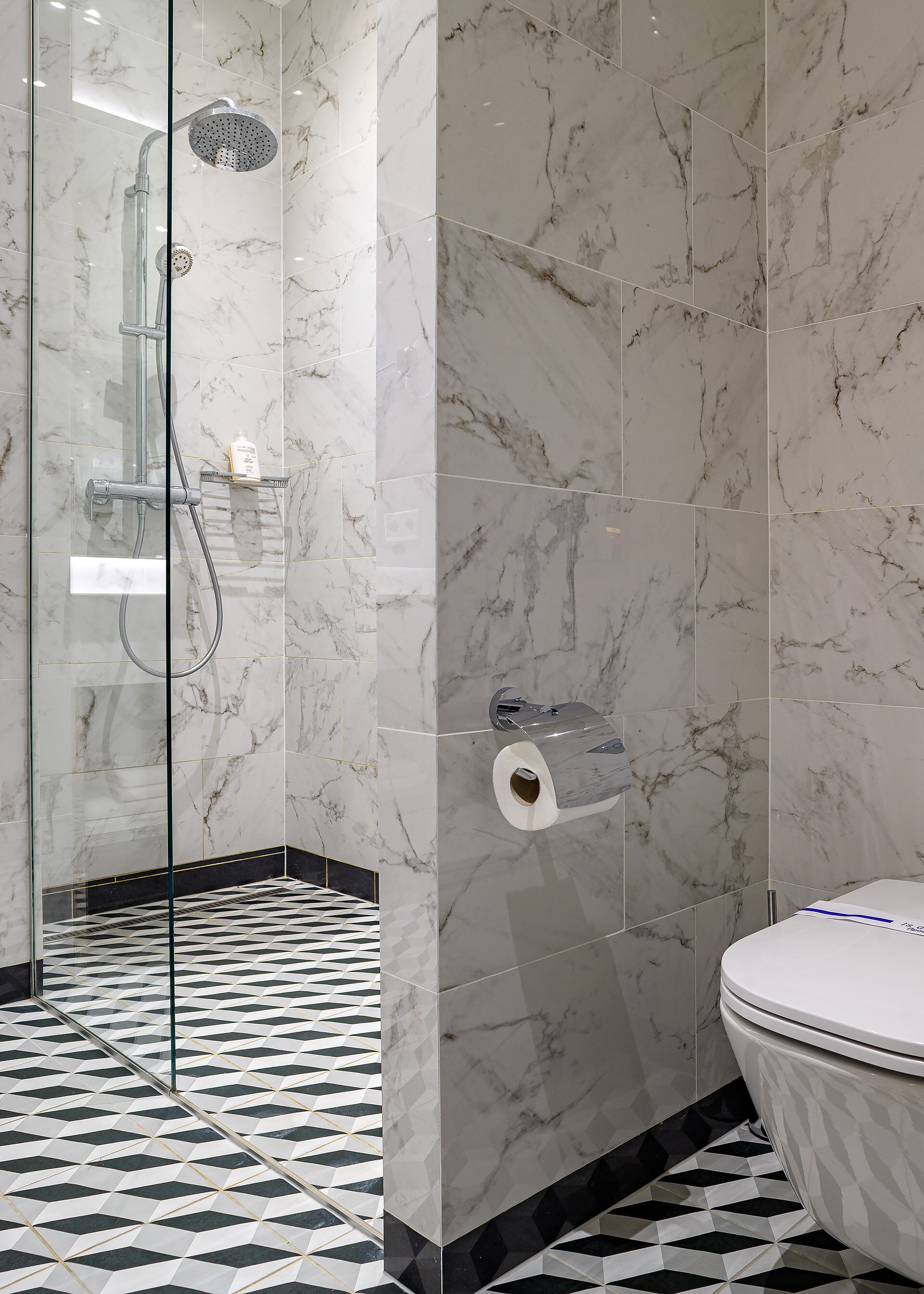 Ein Badezimmer mit Dusche, Toilette und Toilettenpapierhalter an der Wand.