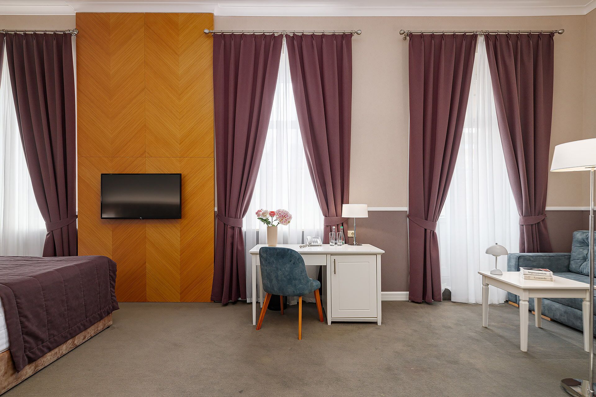 Una habitación de hotel con cama, escritorio, silla y televisor montado en la pared.