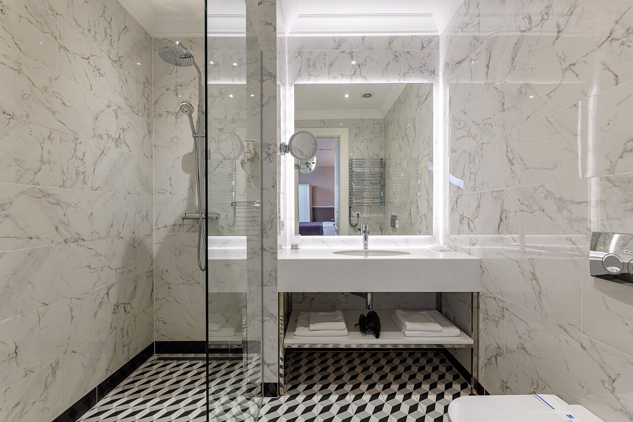 A modern bathroom with a glass-enclosed shower, a white sink, and a black and white checkered floor.