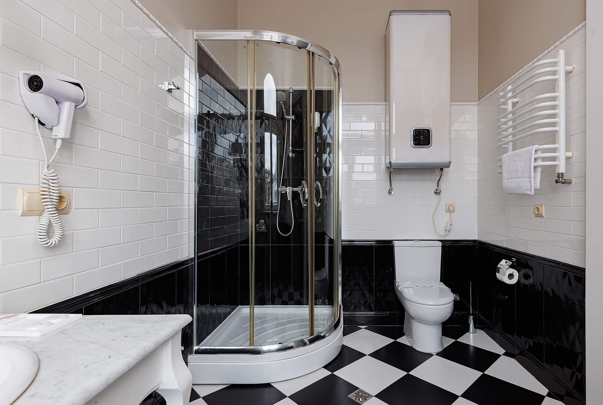 Une salle de bain dotée d’une douche à parois de verre, de toilettes, d’un sèche-cheveux fixé au mur et d’un porte-serviettes.