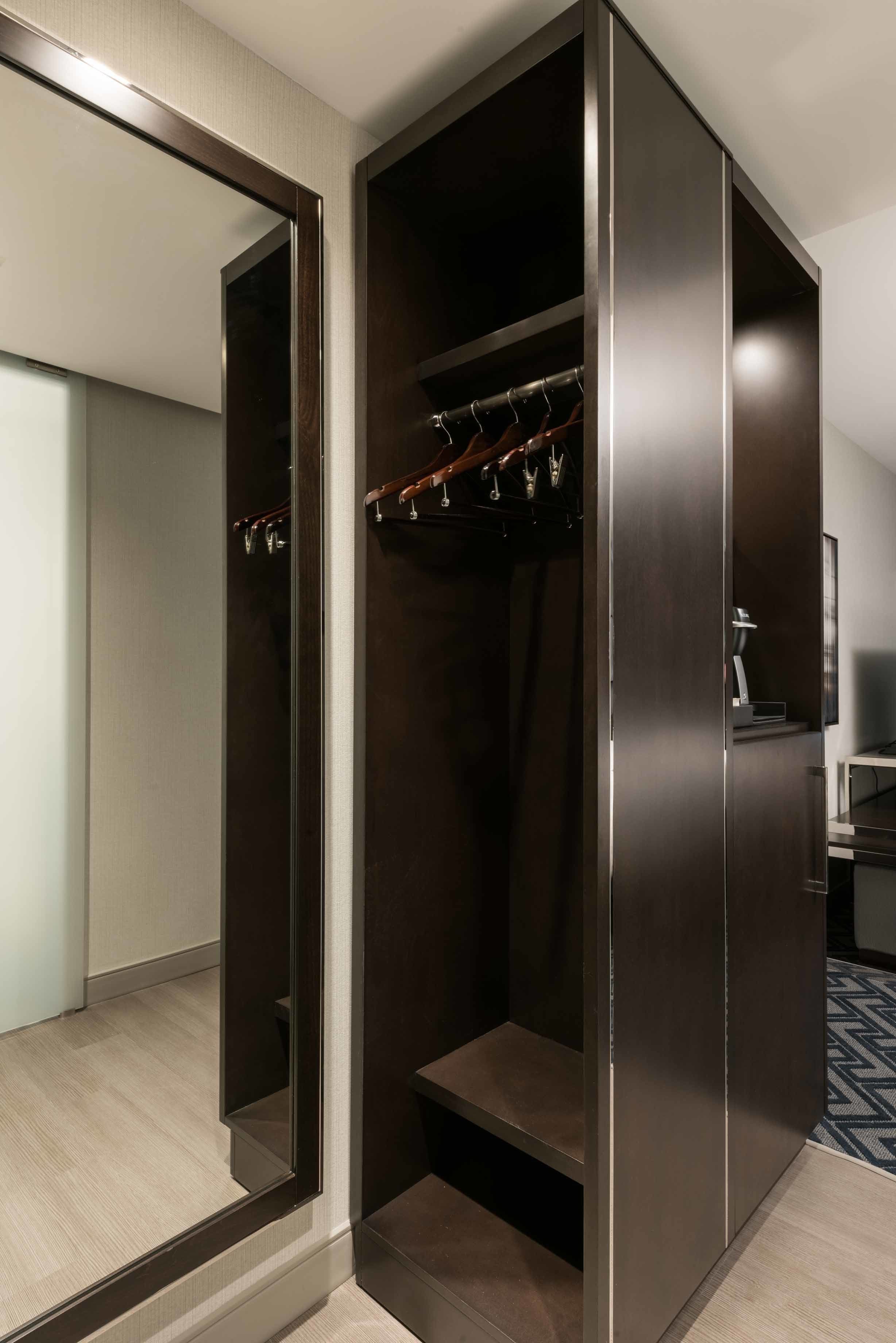 Un dressing accessible sans porte, doté d’une porte de placard miroir, d’un porte-chaussures et d’un petit marchepied menant à un niveau inférieur.