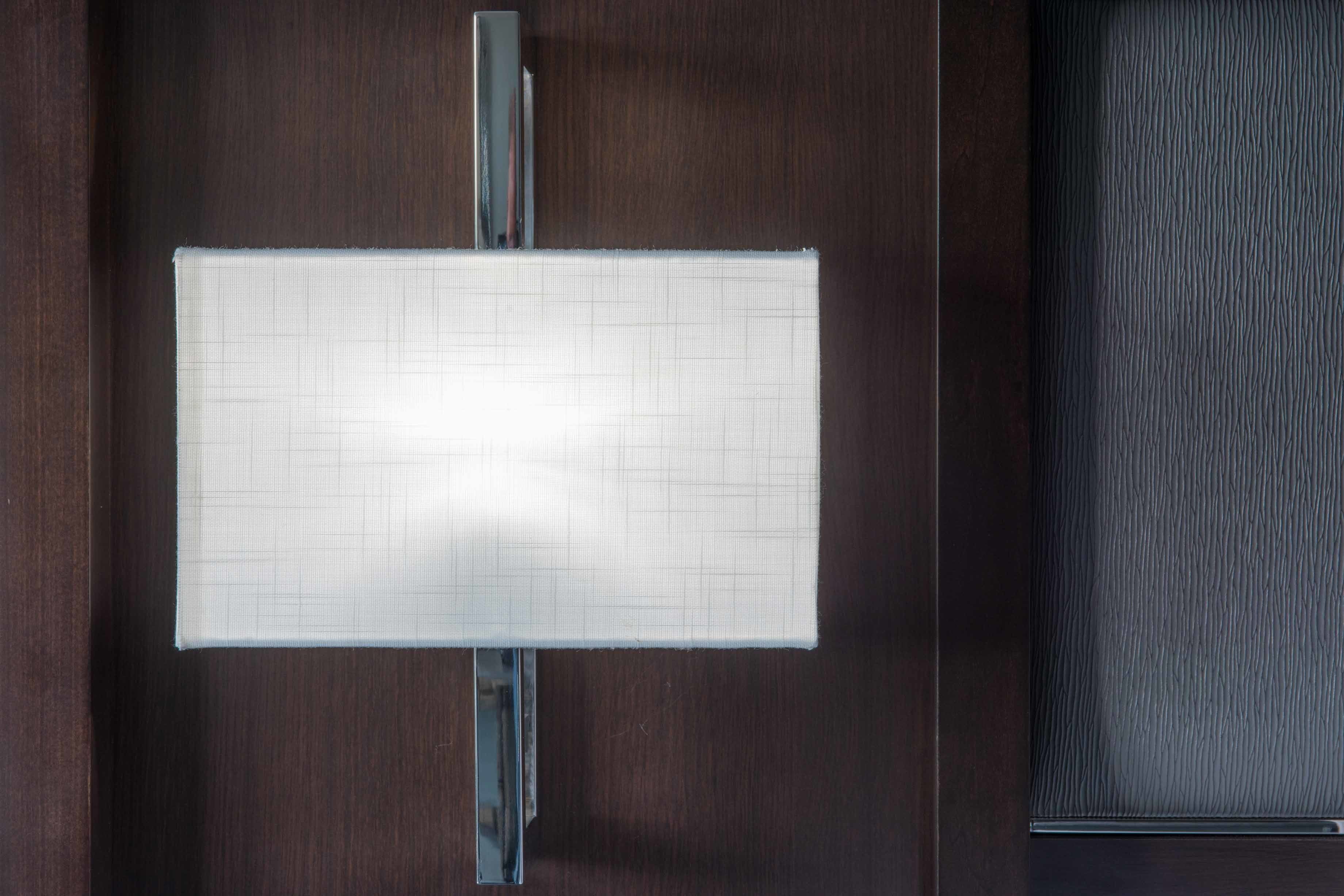 Une porte en bois sombre, ornée d’une enseigne blanche à motifs géométriques, fixée sur un support argenté.