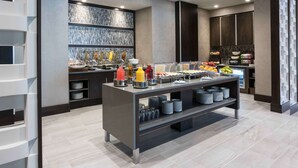 A modern buffet setup with a variety of food options, including fruits, juices, and prepared dishes. - Hilton Garden Inn Foxborough Patriot Place (Foxborough)