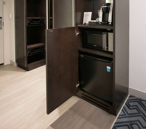 A compact kitchenette with a microwave, coffee maker, and refrigerator.