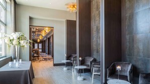 A modern hotel lobby with a seating area, a reception desk, and a decorative vase with flowers. - Hilton Garden Inn Foxborough Patriot Place (Foxborough)