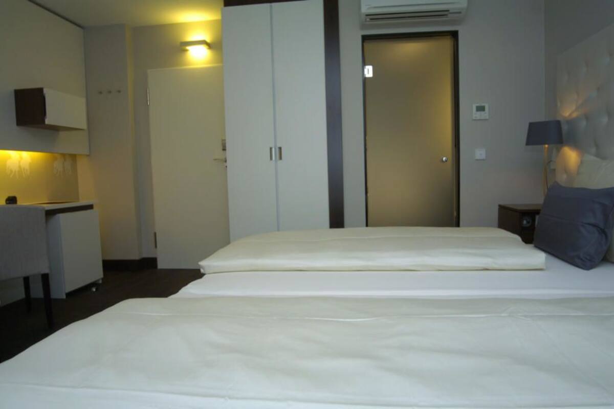 Une chambre d’hôtel avec un lit, un bureau et une armoire.