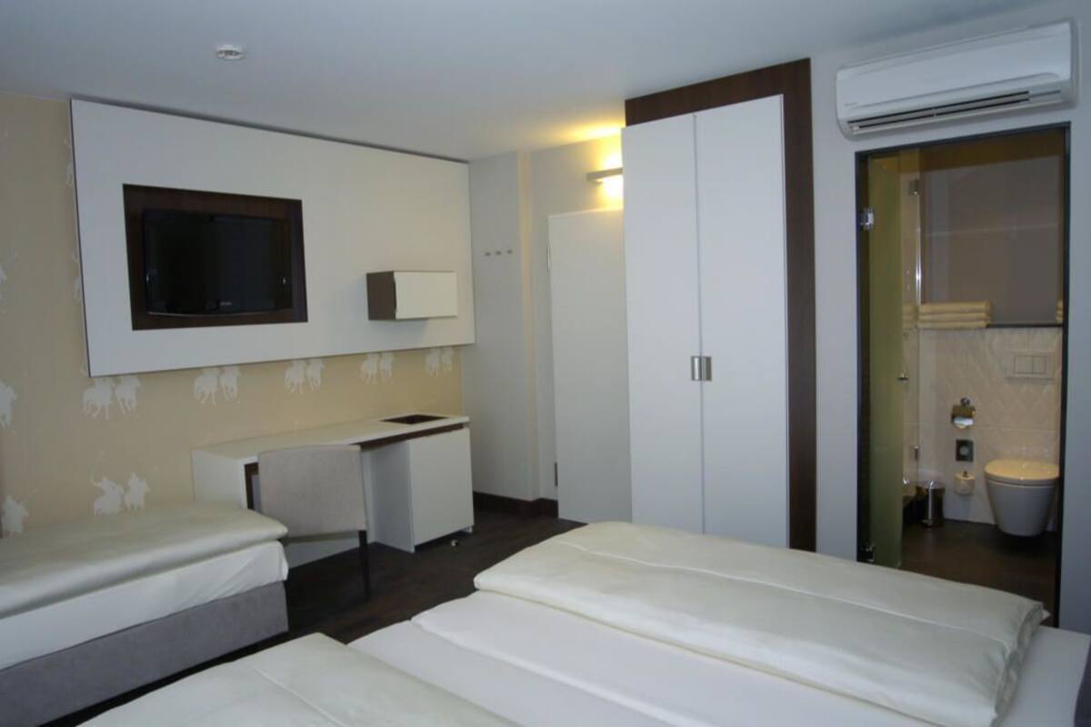 Une chambre d’hôtel avec deux lits, un bureau, une armoire et un appareil de climatisation.
