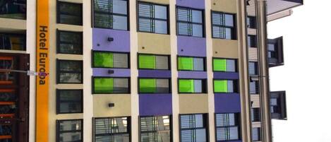 A multi-story hotel building with a modern facade, featuring a mix of window styles and colors.