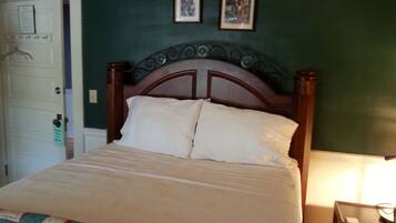 A bedroom with a wooden bed, a quilt, and two framed pictures on the wall.